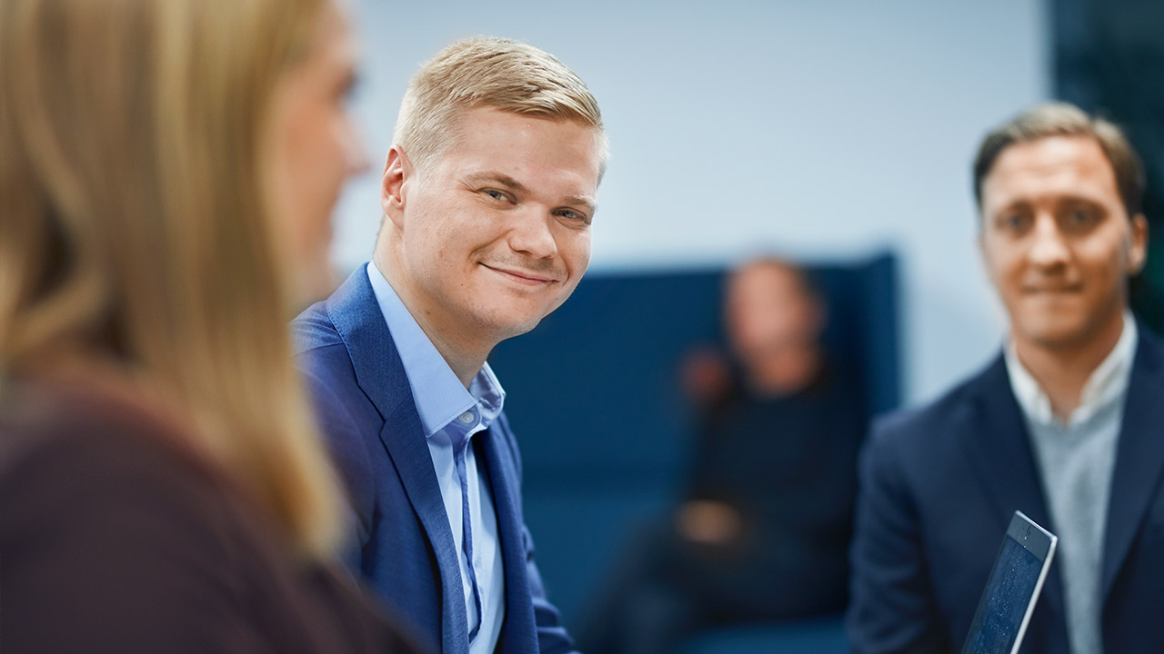 Man smiling in the foreground in conference room