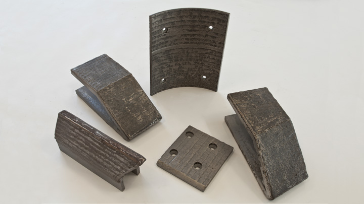 Uma seleção de peças sujeitas ao desgaste feitas de aço com uma camada de revestimento contra desgaste feito de carbonetos