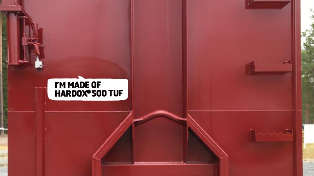 Un contenedor de gancho de color rojo brillante que dice: "Estoy fabricado con Hardox 500 Tuf".