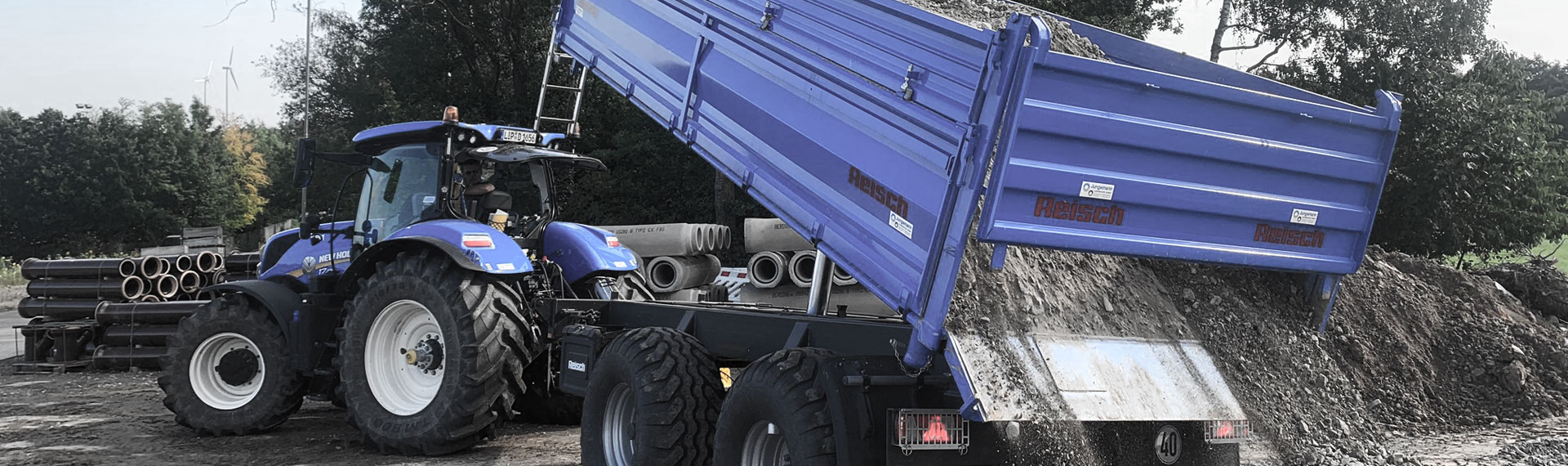 一辆蓝色自卸车，车身由 Hardox® 悍达 ® 薄钢板制成 , 在倾倒大量岩石。