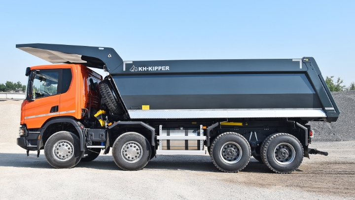 A truck with an orange cabin and black tipper body in Hardox® wear plate