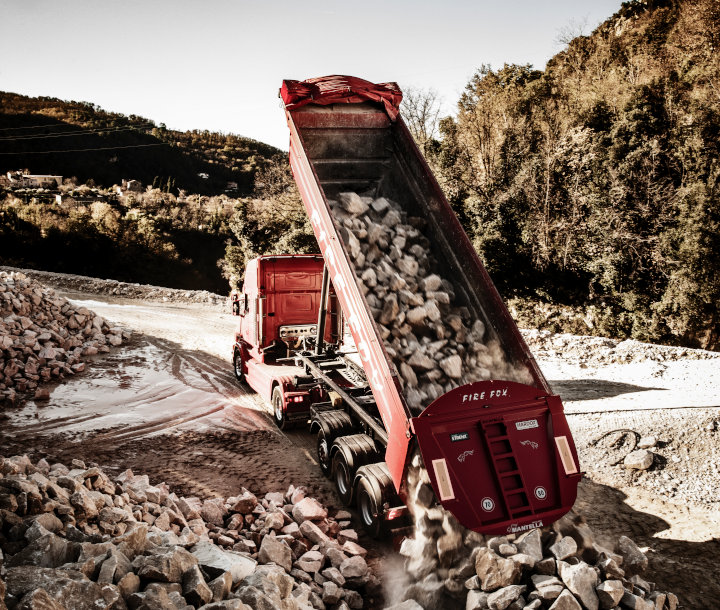 Hardox 耐磨板制成的火红色 Fire Fox 自卸车在倾倒磨蚀性岩石