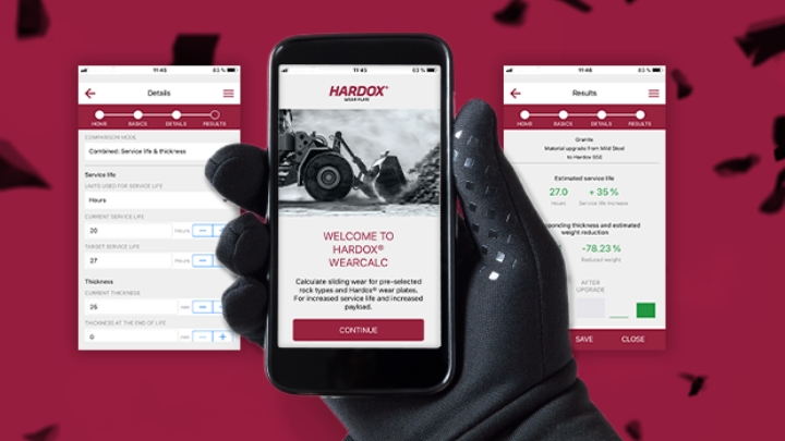A gloved hand holding the Hardox® WearCalc app for calculating equipment wear and service life.