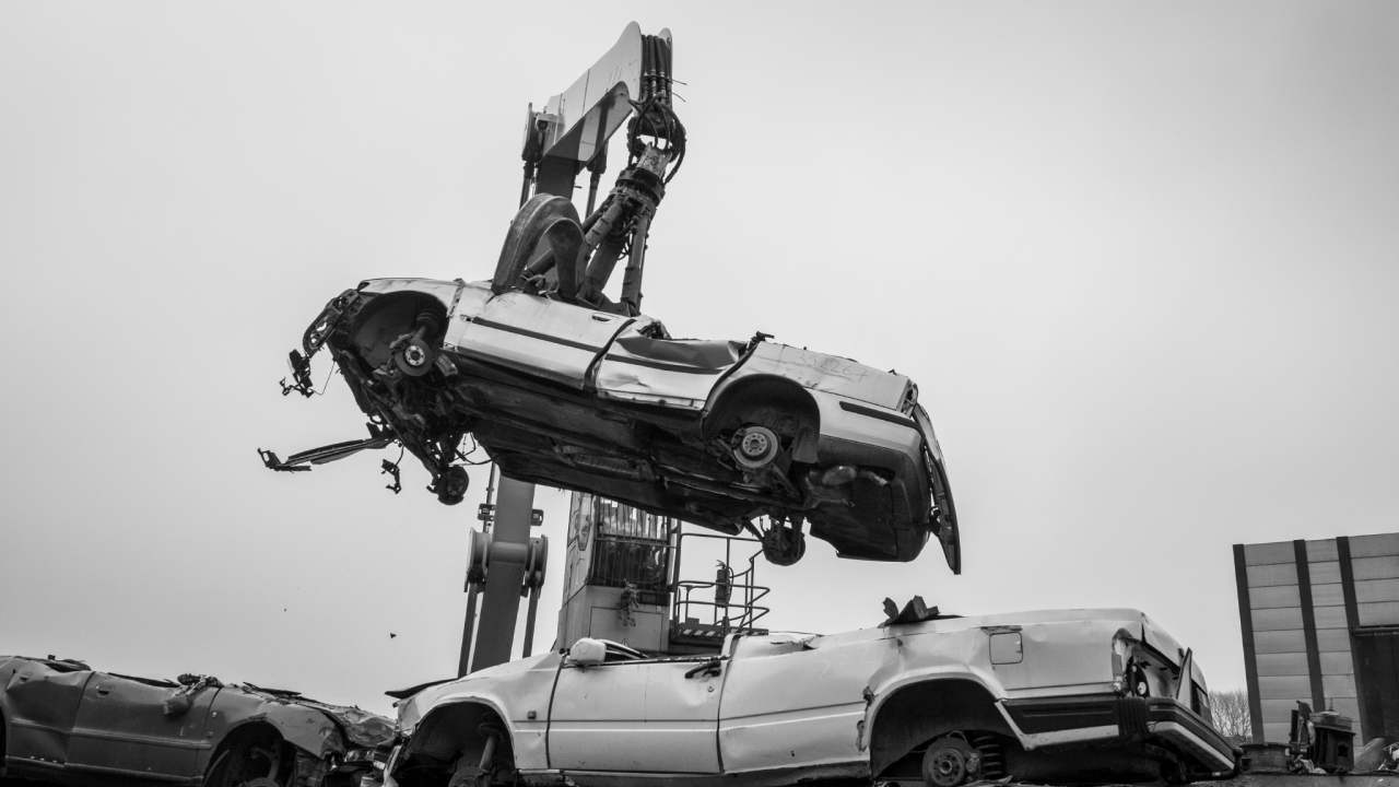A car dangling in the air by a huge grapple, about to be turned into scrap.