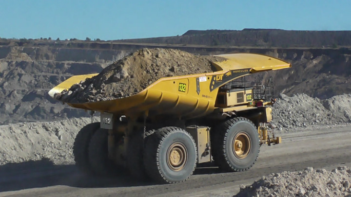A yellow mine dump truck on the road with a heavy load