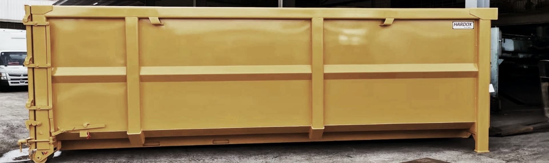 Tyylikäs keltainen teräsjätelava, joka on valmistettu Hardox® HiAce -teräksestä.