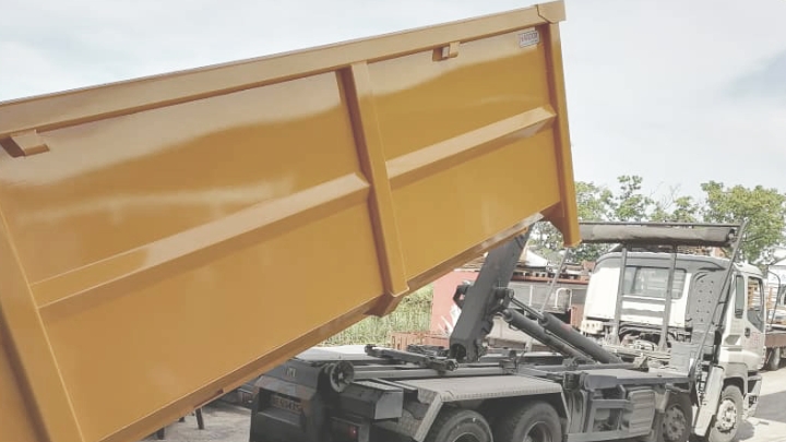 Camion-benne vidant un container à déchets jaune vif en acier résistant à la corrosion.