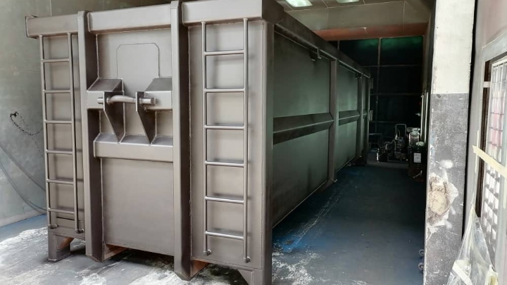 Uma carroceria de contêiner para resíduos cinza com abertura traseira e porta feita com o Hardox® HiAce, um aço resistente à corrosão. 