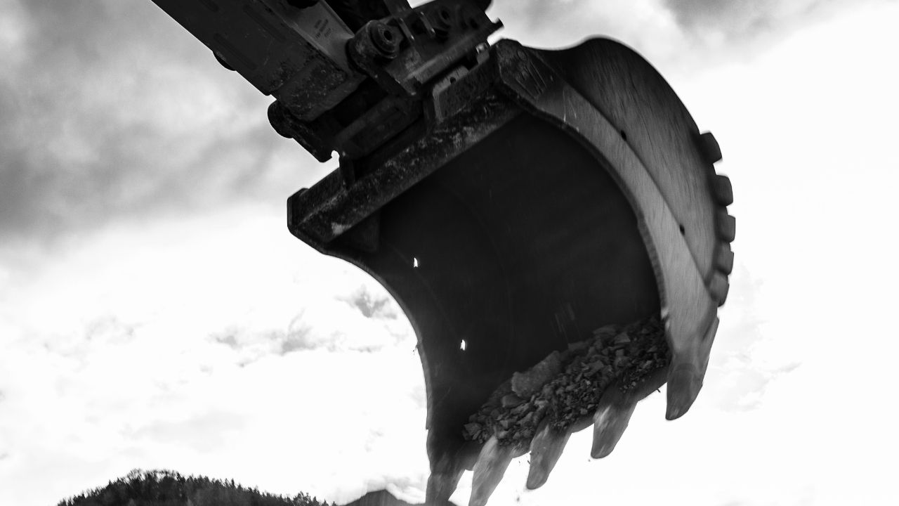 Image en noir et blanc d’un immense godet d’excavatrice en acier anti-abrasion Hardox® dans les airs.