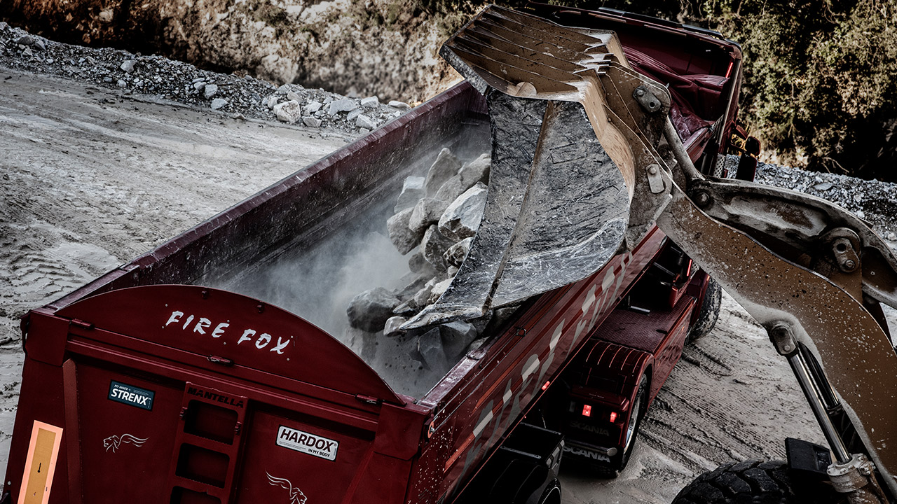 Overhead of a truck body, the Firefox, being loaded with abrasive rocks. 