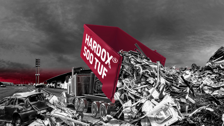 A red dump truck body made in Hardox® 500 Tuf steel, dumping out abrasive waste.
