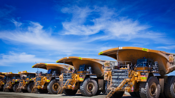 A lineup of yellow mining haul trucks against a bright blue sky, with bodies made in Hardox® 500 Tuf steel.