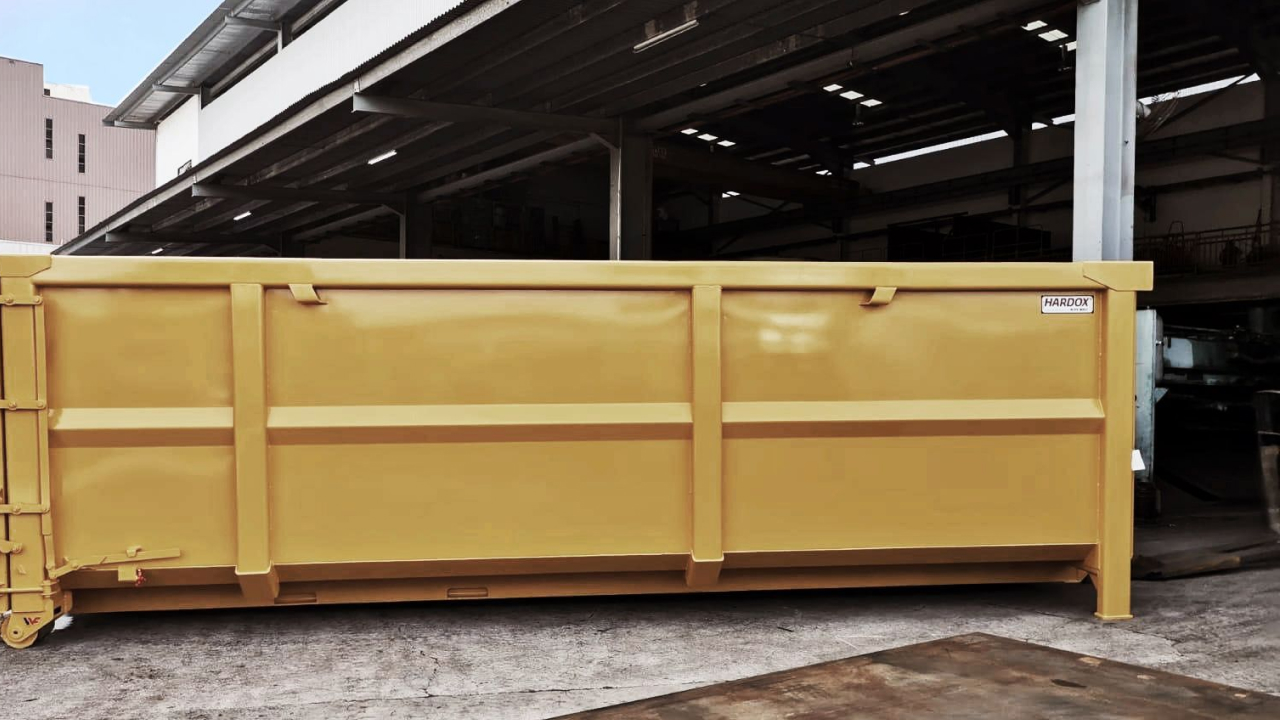 A yellow container made in high-strength steel Hardox® wear plate, with the Hardox® In My Body logo on it.
