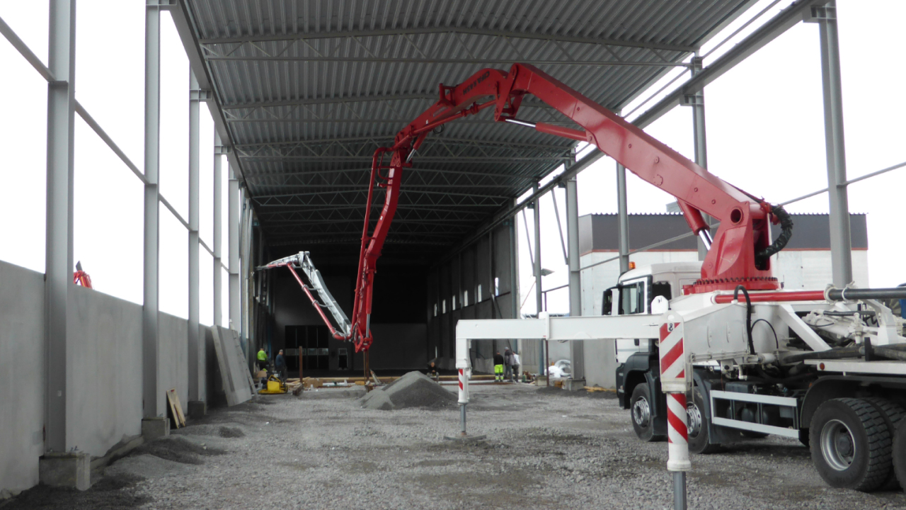A concrete pump truck with tubing made in abrasion-resistant Hardox® pipe pouring a concrete floor in an industrial building
