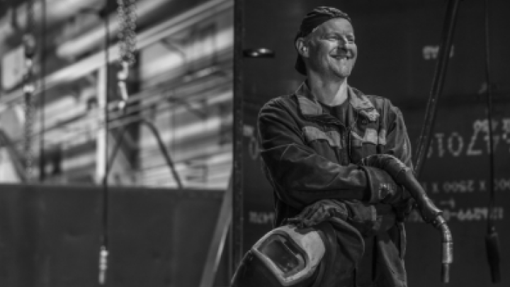 Black and white photo of a man smiling in front of Hardox® steel pipes and tubes