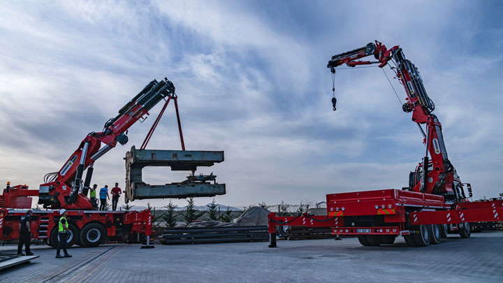 Two bright red cranes doing heavy-duty lifting, with crane booms made in Strenx structural steel.