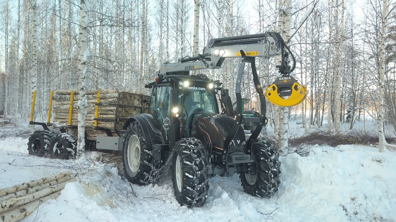 겨울철 숲 속에서 목재 수거 작업 중인 Strenx® 제품으로 제작된 크레인이 장착된 트랙터.